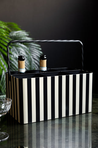 The Monochrome Stripe "Booze" Wine Bottle Carrier seen from the back, styled with some bottles, a glass and some greenery.