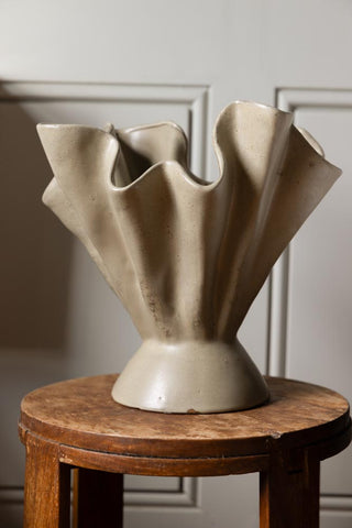 Beautiful pleated vase on a wooden bar stool.