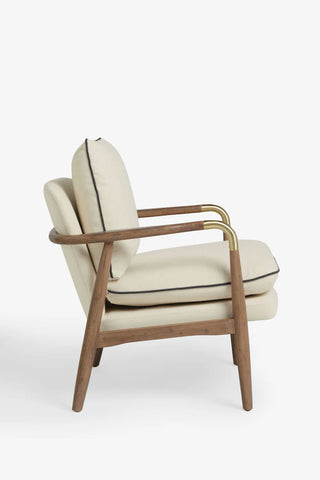 Natural armchair with wooden frame and brass accents, seen from the side on a white background.