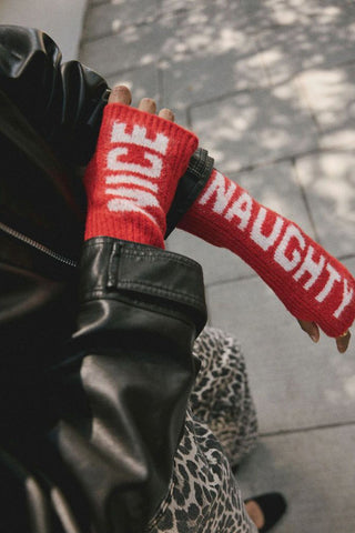 The Naughty or Nice Handwarmers being worn by a model standing on the pavement.
