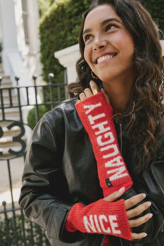 The Naughty or Nice Handwarmers being worn by a smiling model with their arms crossed up to their chest, standing outdoors.