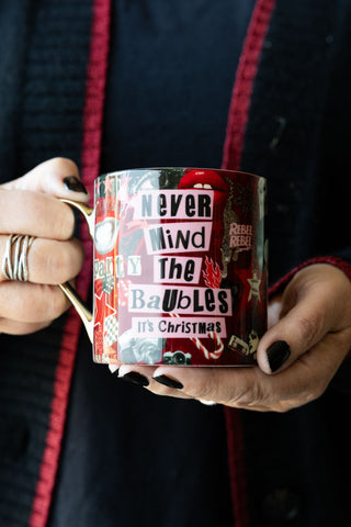 The Never Mind The Baubles Mug being held by a model.