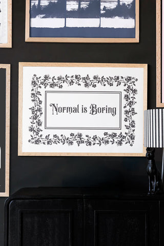 Framed art print with 'Normal is Boring' text on a black wall