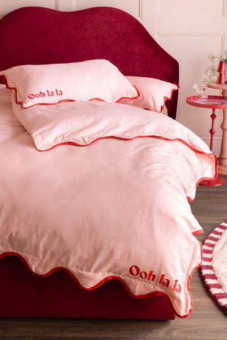 The Ooh La La Pink & Red Scallop Edge Bedding Set styled on a bed.