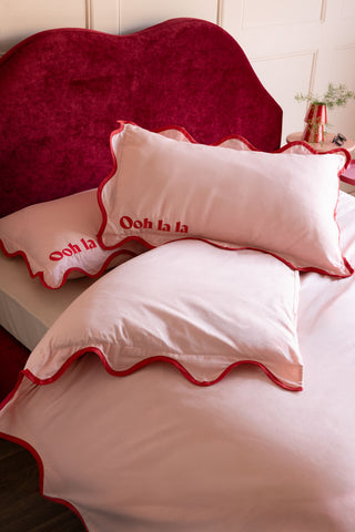 The Ooh La La Pink & Red Scallop Edge Bedding Set styled on a red lips bed.