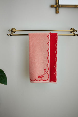 The Ooh La La Hand Towel displayed on a towel rail on the wall, with a mirror and plant also in the shot.
