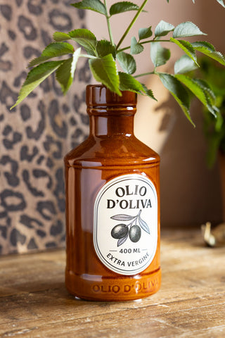 Olio d'Olivia Ceramic Bottle Vase shown in a kitchen with green foliage. 