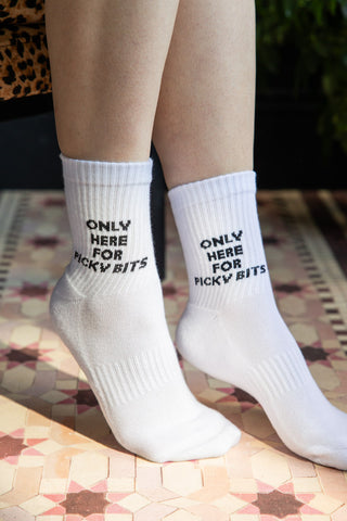 The Picky Bits White Socks shown on a model against a pink star tile-effect floor. 