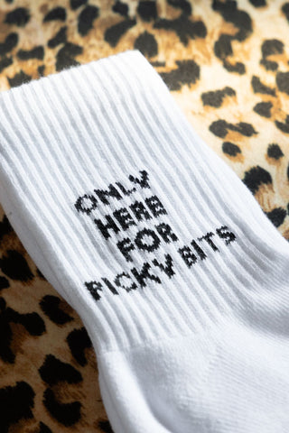 The Picky Bits White Socks shown against a leopard print background. Socks are white sports socks with black text that says 'only here for picky bits'.