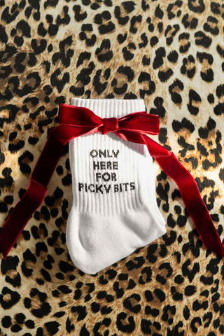 The Picky Bits White Socks shown with a red bow against a leopard print background. 