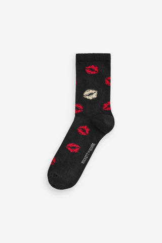 A pair of black socks with lips pattern on a white background.