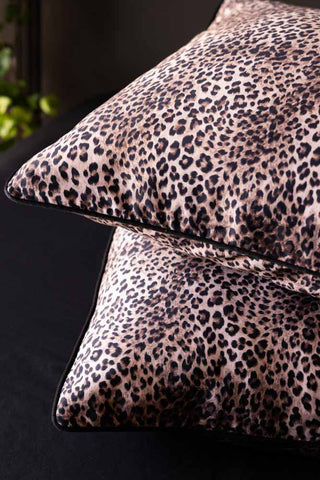 Two leopard print pillows on a dark sheet.