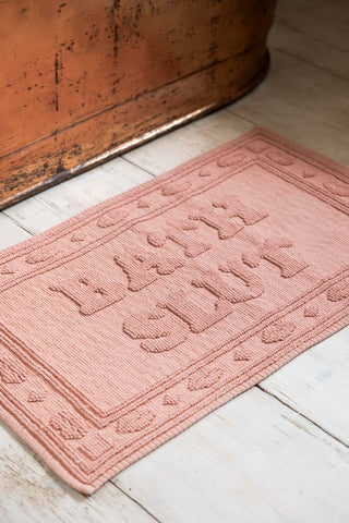 Bath Slut Blush Pink Bath Mat shown against a copper bath. 