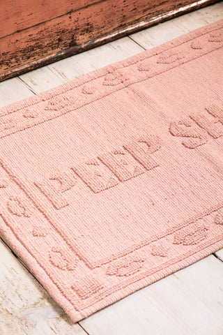 Close-up of a pink bath mat with text on.