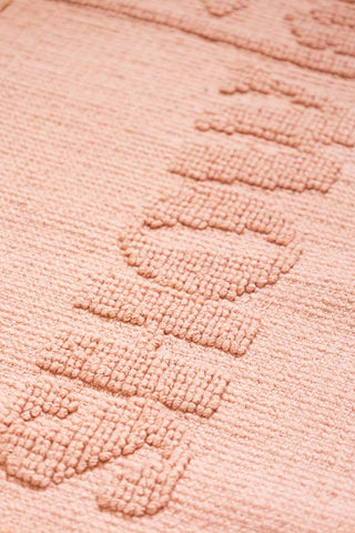 Close-up of the text on a textured pink bath mat.