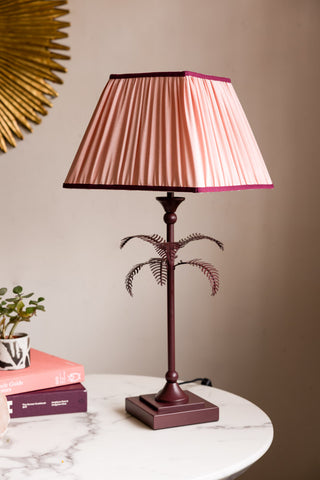 Styled image of the Palm Tree Table Lamp - Pink & Burgundy, switched off and on a white marble table