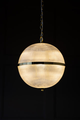 The Parisian Gold & Glass Pendant Ceiling Light switched on in front of a dark wall.