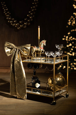 The Party People Only Gold Drinks Trolley shown in a party setting with wood walls, gold accessories and etched champagne glasses. 