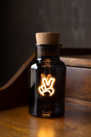 The Peace Neon Bottle Light displayed on a wooden surface.