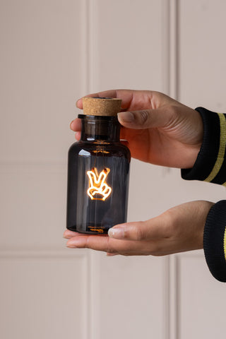 The Peace Neon Bottle Light being held in a model's hands.