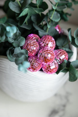 Bunch of pink disco ball lights next to eucalyptus in a planter