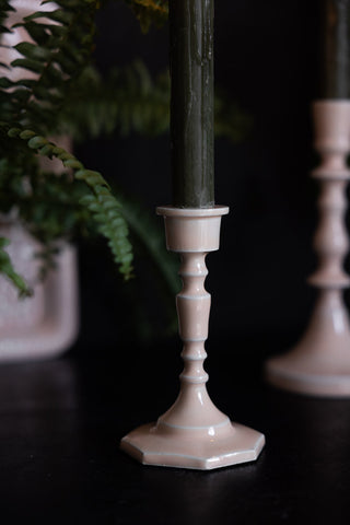 Detail shot of the short Pink Enamel Cast Style Candlestick Holder displayed on a black sideboard with candles in and with a plant in the background.