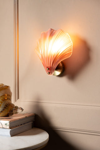 Stunning Pink Glass Shell Wall Light shown with the light on against a beige panelled wall