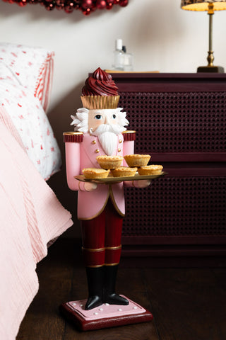 The Pink Nutcracker Butler Christmas Decorations styled with some mince pies on next to a bed.