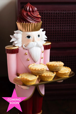 The Pink Nutcracker Butler Christmas Decoration styled with some mince pies on. The image includes a pink star icon with the words 'coming soon'.