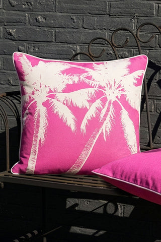 Two of the Pink Palm Tree Outdoor Cushions styled on a bench outdoors.