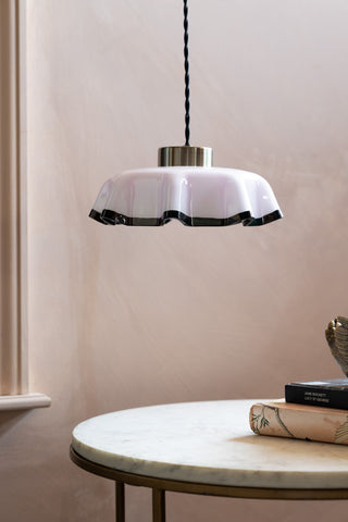 The Pink Pleated Glass Easyfit Ceiling Light Shade shown against plastic pink walls, hanging over a coffee table. 