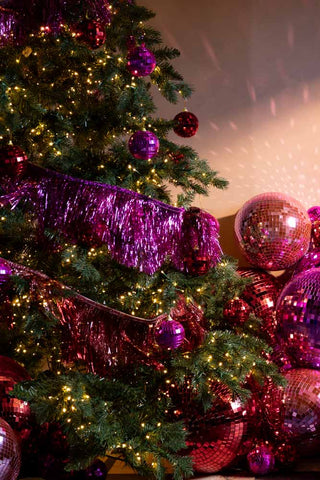 The Pink Scalloped Tinsel Garland styled on a Christmas tree with various disco ball decorations.