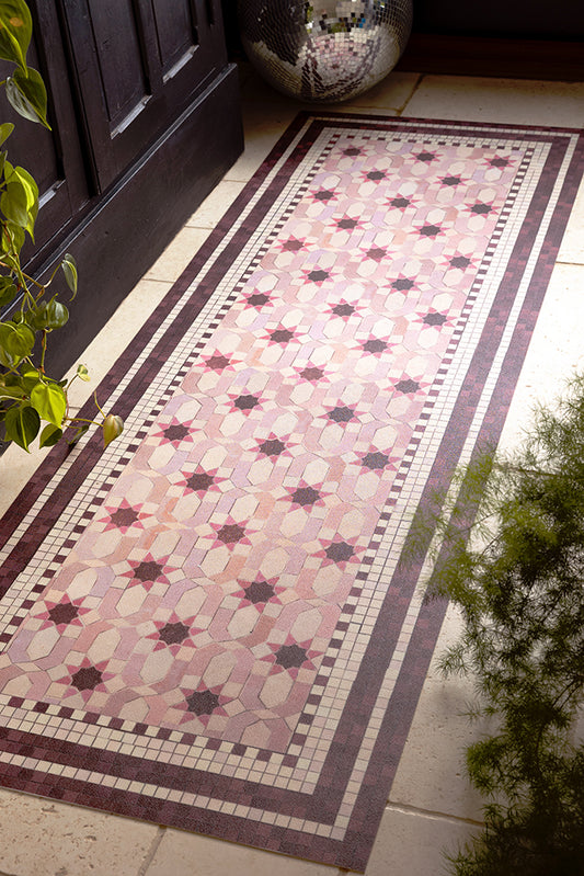 The Pink Star Durable Runner shown on stone flooring against a black kitchen cabinet and with a disco ball in the background. 