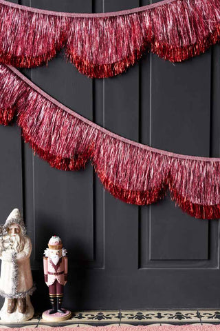 Lifestyle image of the Pink Tinsel Scalloped Decorative Garland on a door