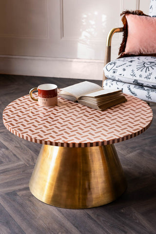The Pink & Caramel Inlay Coffee Table with a mug and book on, styled in front of a chair.