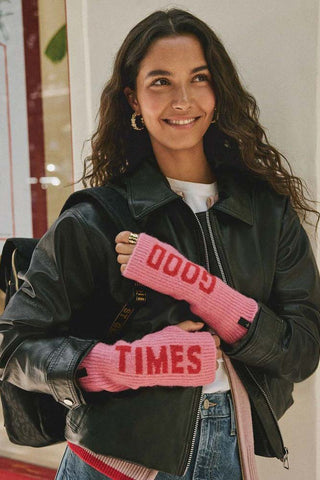 A model wearing the pink and red good times handwarmers, holding the strap of her backpack.