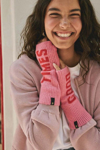 A model wearing the pink and red good times handwarmers, smiling and holding her hands up to her face.