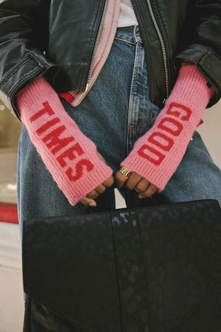 Close-up of a model wearing the pink and red good times handwarmers, holding a bag.