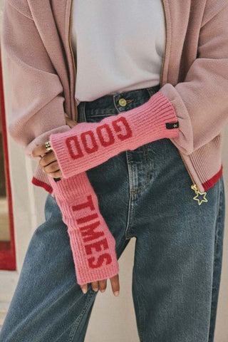 Close-up of a model wearing the pink and red good times handwarmers, holding their arm with one hand.