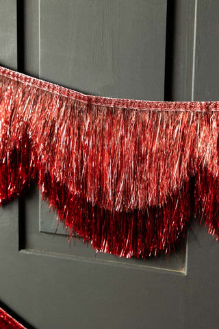 Close-up of the Pink & Red Scalloped Tinsel Garland on a black background.