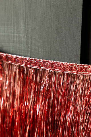 Close-up of the edge of the Pink & Red Scalloped Tinsel Garland on a black background.