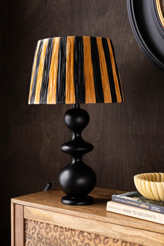 The Raffia Black & Natural Stripe Easyfit Lampshade on a wooden sideboard.