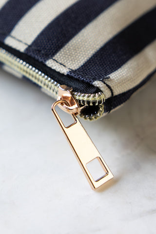 The gold zip on the Random Crap Striped Canvas Pouch. 