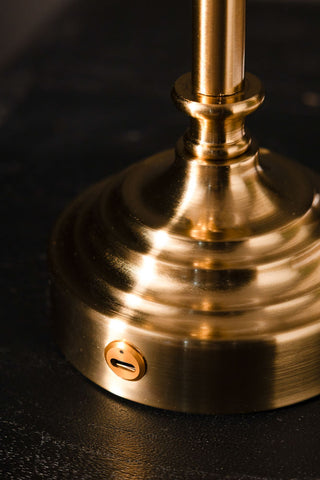 Close-up of a brass table lamp on a dark background.