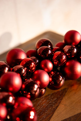 Close-up of the Red Bauble Cluster Christmas Garland on a wooden surface.