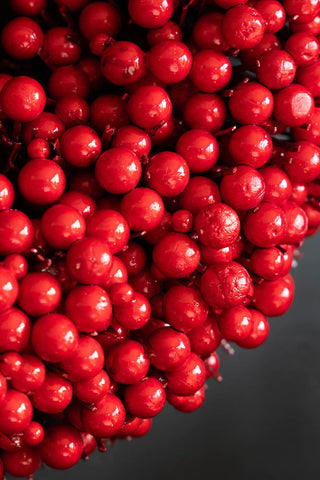 Close-up of the Red Berry Christmas Wreath in front of a black background.