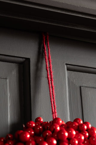 Close-up of the hanging loop on the Red Berry Christmas Wreath in front of a door frame.