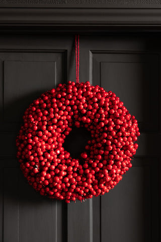 The Red Berry Christmas Wreath hanging on a black door.