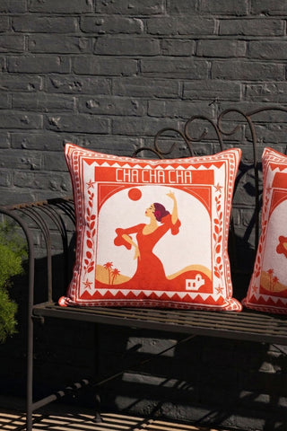 Two of the Red Cha Cha Cha Outdoor Cushion, styled outdoors on a garden bench.