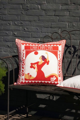 The Red Cha Cha Cha Outdoor Cushion styled on a garden bench.
